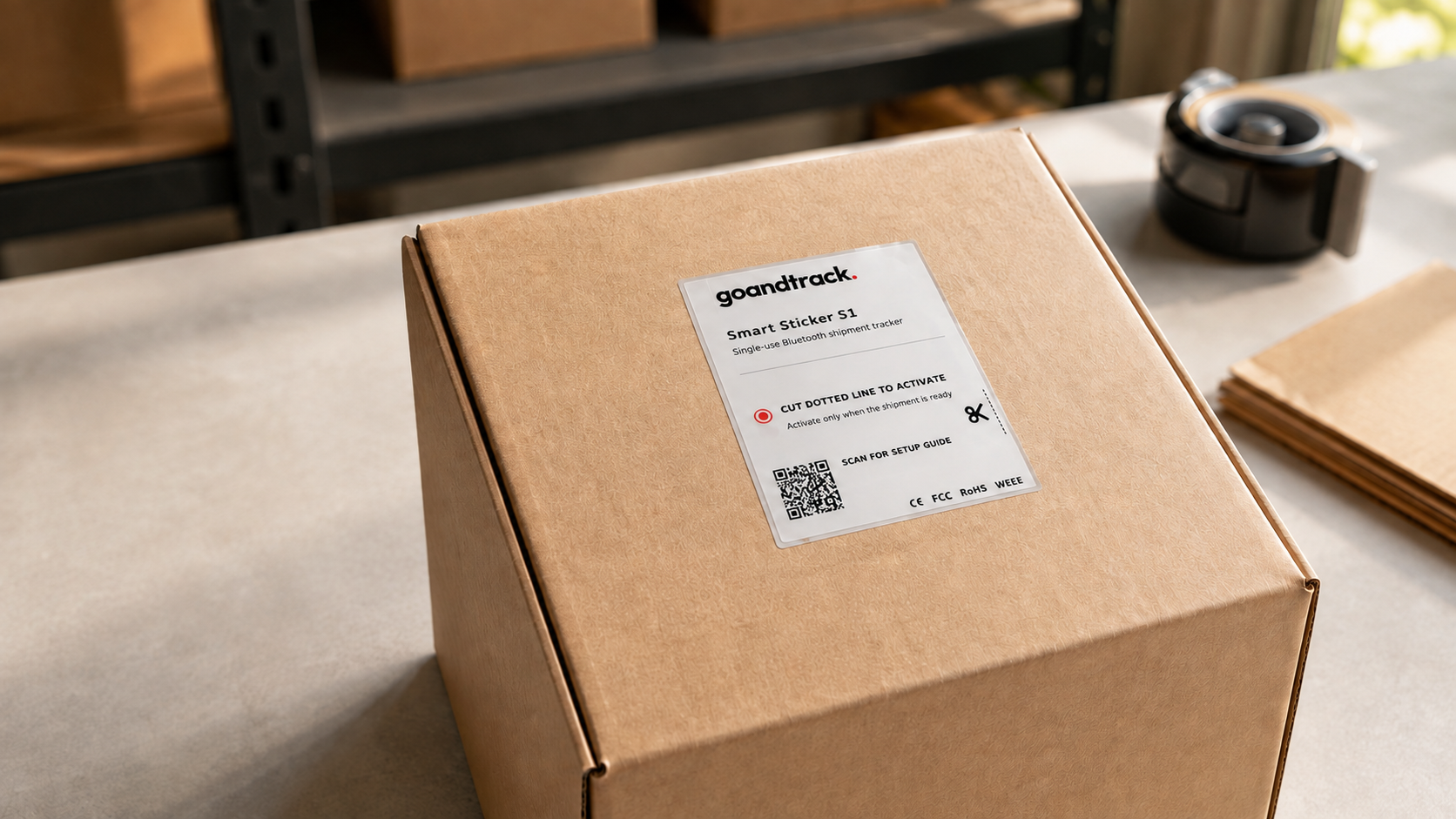 GoAndTrack Smart Sticker S1 applied to the top of a sealed cardboard box on a packing bench